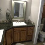 A newly remodeled custom bathroom with black granite countertop, wooden cabinets, and white wood trimming