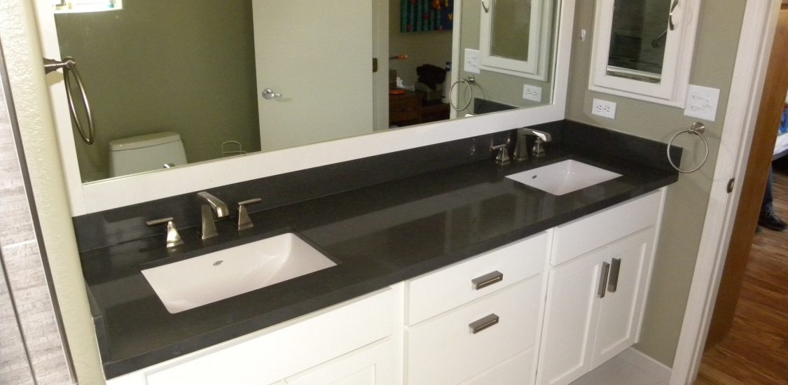After photo of a custom designed bathroom with black countertops and white wooden cabinets in a residential bathroom.