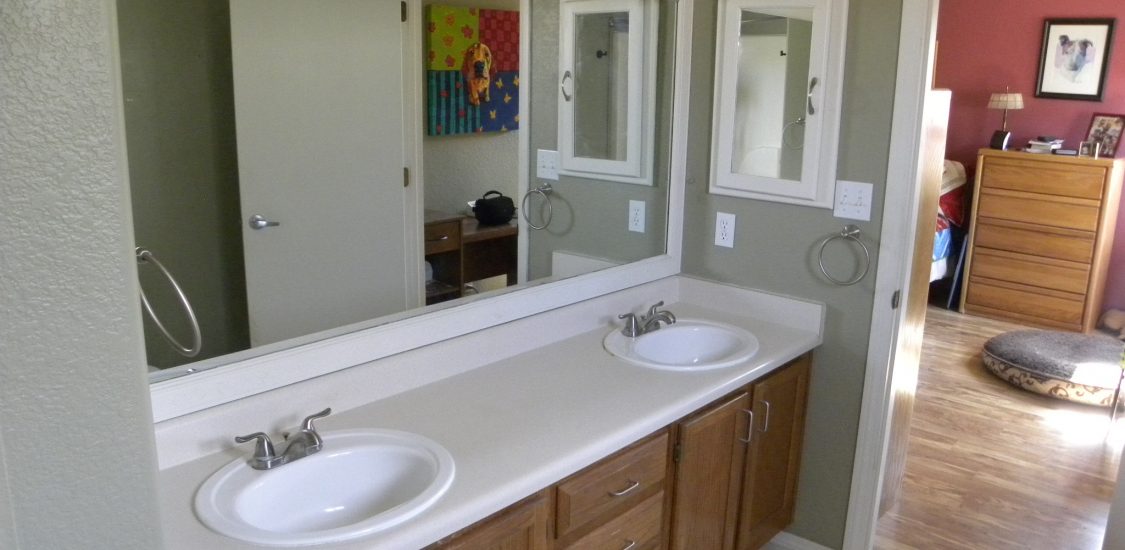 Before photo of a bathroom with white countertop and wooden cabinets in a residential bathroom.