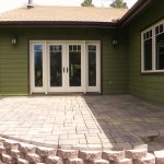 Exterior shot of a residential home with a stoned patio and white trimmed doors/windows