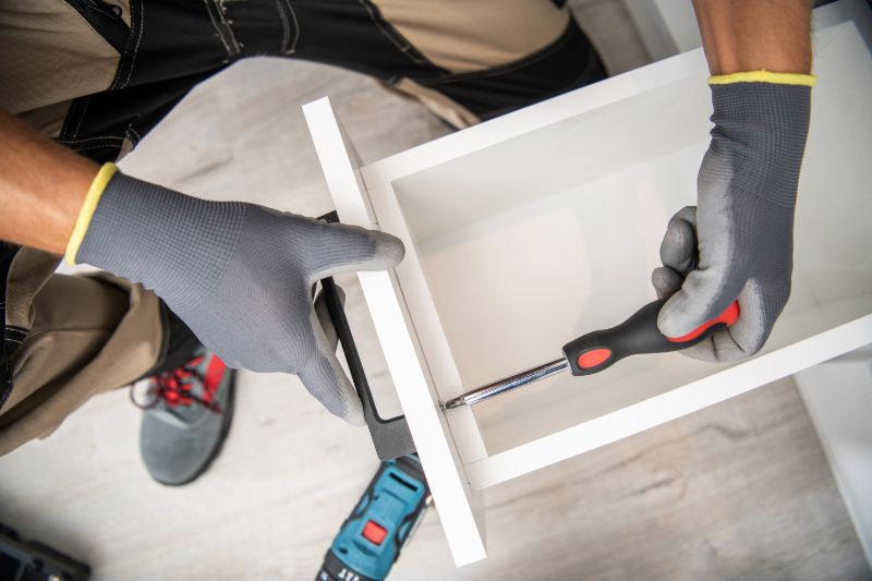 A contractor is installing new hardware during a kitchen remodel
